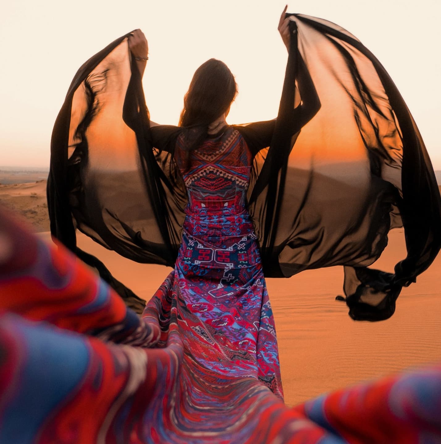 Woman with black silk veil in desert sunset