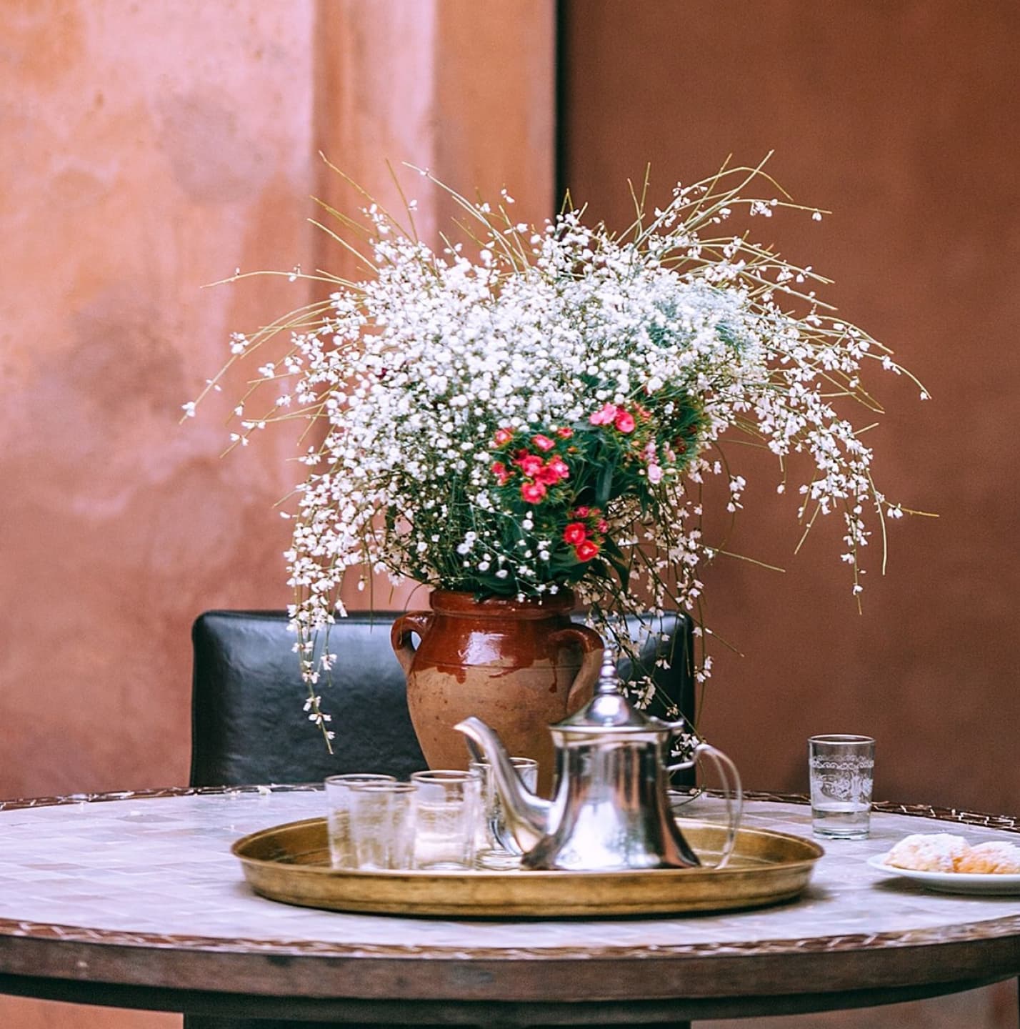 Floral arrangement and traditional teapot on round table